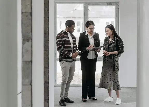 A realtor discussing with a prospective buyer couple inside a house
